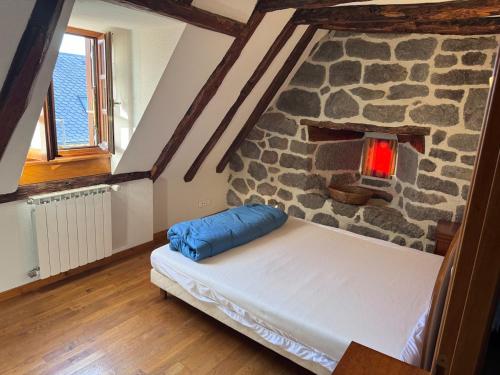 a bed in a room with a stone wall at Le relais de Lustrande in Brezons