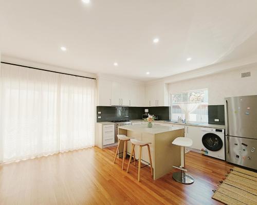 a large kitchen with a counter and chairs in it at Easy access to city park side cosy house in a convenient hub in Sydney