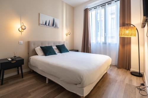 a bedroom with a large white bed with blue pillows at Chambre 5 La Baieta in Nice