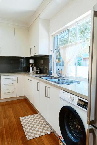 a kitchen with a washing machine in the middle of a dishwasher at Easy access to city park side cosy house in a convenient hub in Sydney