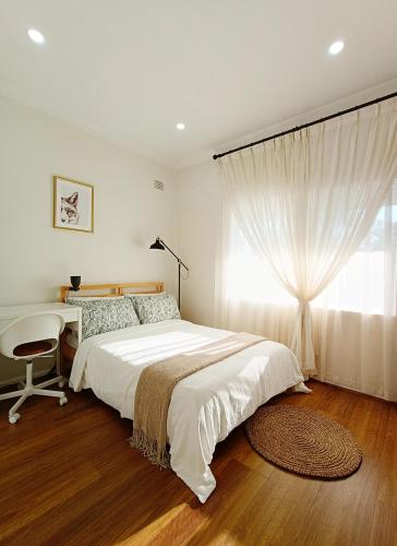 a bedroom with a bed and a desk and a window at Easy access to city park side cosy house in a convenient hub in Sydney