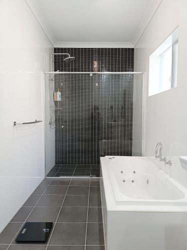 a white bathroom with a tub and a shower at Easy access to city park side cosy house in a convenient hub in Sydney
