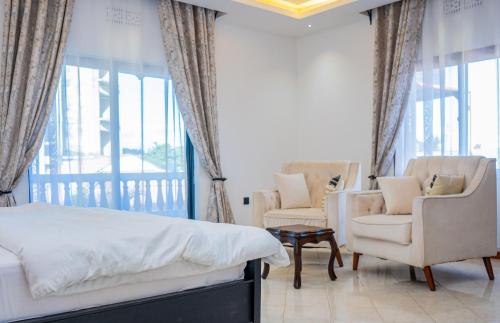 a bedroom with a bed and two chairs and a balcony at AG Comfort Homes in Nkunjila