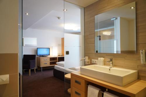 a bathroom with a sink and a desk with a computer at Quality Hosts Arlberg - Hotel Goldenes Kreuz B&B - Sommerkarte Premium inklusive in Sankt Anton am Arlberg