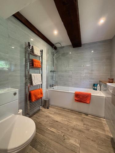 a bathroom with a tub and a toilet with orange towels at Cosy coastal hideaway with incredible sea views in Fortrose