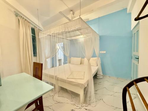 a white room with a bed and a table at Shells Unawatuna in Unawatuna