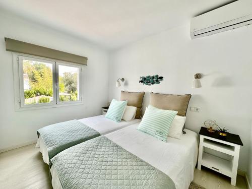 a white bedroom with a large bed and a window at Villa Colibrí, con piscina privada para 6 personas in Santa Ponsa