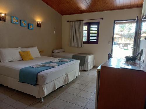 a bedroom with a bed and a desk in it at Hotel Enseada Maracajaú in Maracajaú