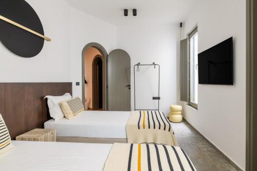 a hotel room with two beds and a flat screen tv at Koniko Santorini Private Pool Villas in Vóthon