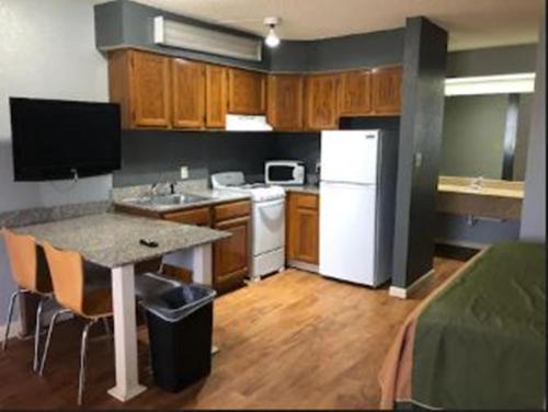 a small kitchen with a white refrigerator and a table at Americas Best Value Inn Yukon in Yukon