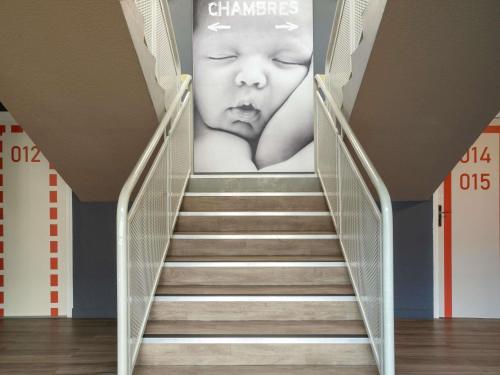 a staircase with a poster of a baby on the wall at ibis budget Rennes Chantepie - Hôtel rénové in Chantepie