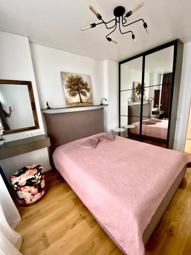 a bedroom with a pink bed and a mirror at Modern 3-bedroom jacuzzi apartment in Lviv