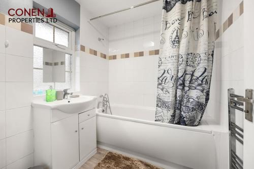 a bathroom with a tub and a sink and a shower curtain at CONEN Morant Place in Grays Thurrock