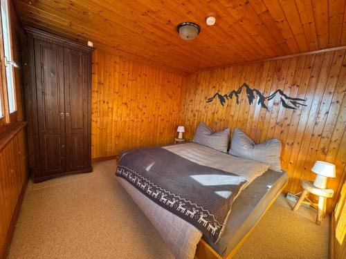 a bedroom with a bed in a wooden wall at Charming Chalet Silvretta in Flumserberg in Flums