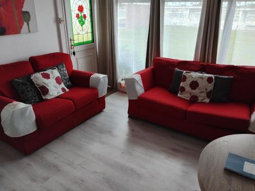 a living room with two red couches and a table at "Trinity" Chalet in Sundowner Hemsby in Hemsby