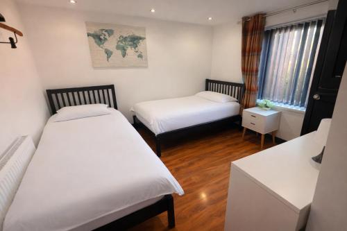 a small room with two beds and a desk at Tarleton Guesthouse in Stoke on Trent