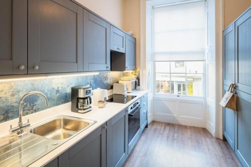 a kitchen with blue cabinets and a sink at Stylish Retreat in Central Lyme Regis Sleeps 2 plus one in Lyme Regis