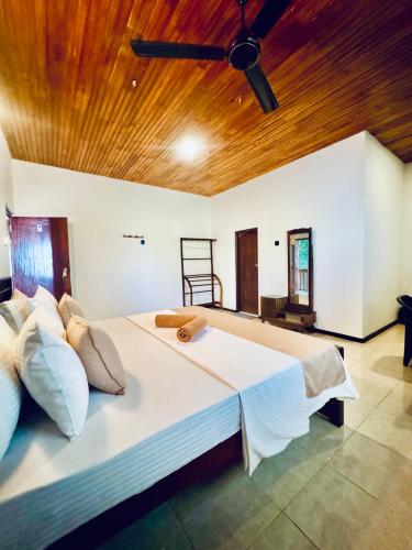 a bedroom with a large white bed with a wooden ceiling at Asiri guest house in Dickwella
