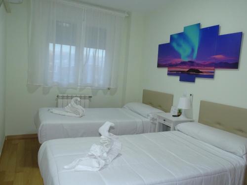ein Zimmer mit drei Betten mit weißer Bettwäsche in der Unterkunft Brezo 2 in Yunquera de Henares