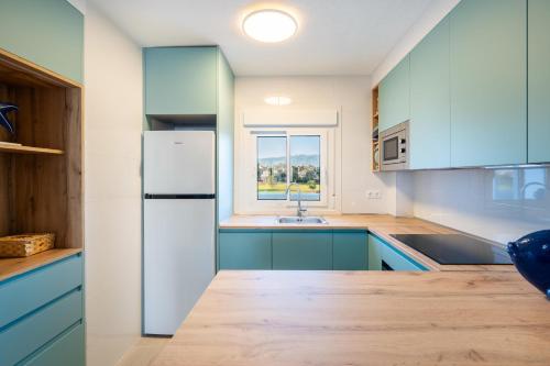a kitchen with blue cabinets and a white refrigerator at Apartamento isabel golf center in Almería