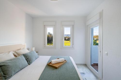 a white room with a bed and two windows at Apartamento isabel golf center in Almería