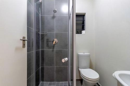 a bathroom with a shower with a toilet and a sink at The Waterfallcity Charm next to Mall of Africa in Midrand