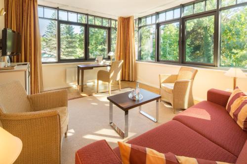 a living room with a couch and chairs and windows at Parkhotel Güldene Berge in Weißenfels