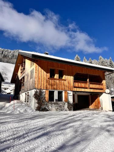 a wooden building in the snow with a snow covered driveway at Appartement Chalet Louison in Les Gets