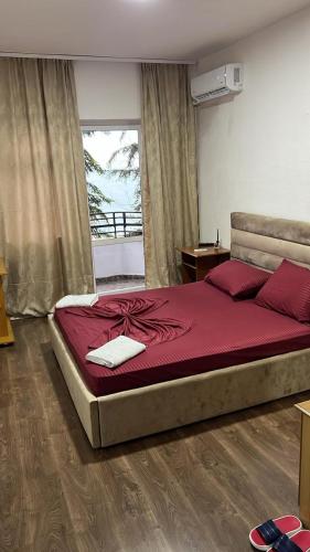 a bedroom with a large bed with red sheets at Hotel Te Bakja in Tushemisht