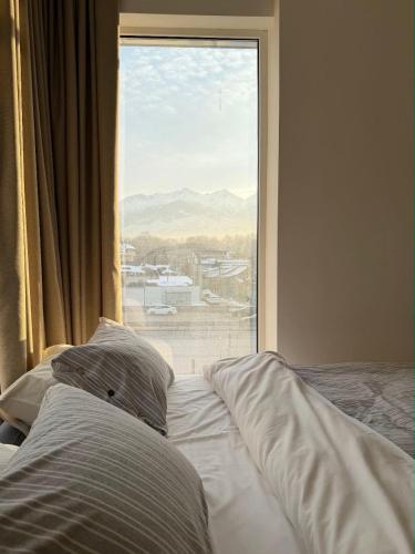 a bed in front of a window with a view at Mosh Mosh Boutique Hotel in Almaty