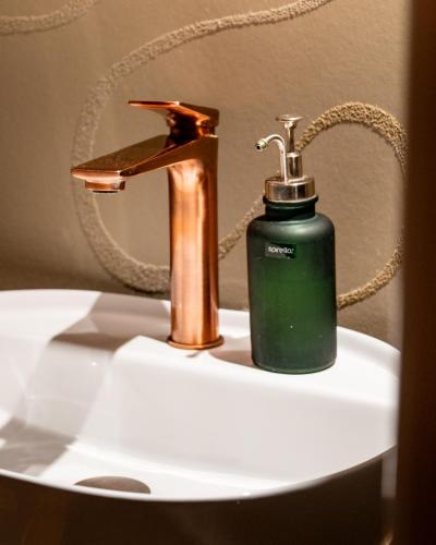 a soap dispenser sitting on a sink next to a faucet at Sérénité Einigen Chalet in Einigen