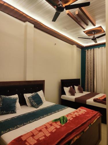 a bedroom with two beds and a ceiling fan at Akshayavat Palace in Ayodhya