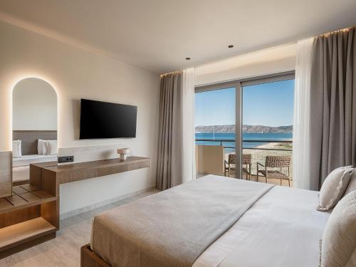 a hotel room with a large bed and a television at Sunny Bay Hotel in Kissamos