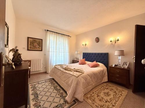 a bedroom with a bed with a blue headboard and a window at Casa Santa Bárbara in Manteigas
