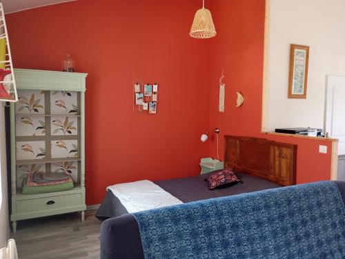 a bedroom with red walls and a bed and a dresser at Gite Le Gripeau in Apremont