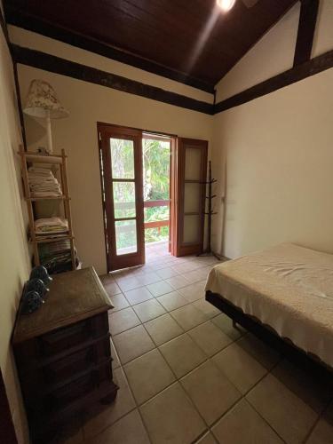 a bedroom with a bed and a window and a door at Canto do Cururuá - IlhaBela in Ilhabela