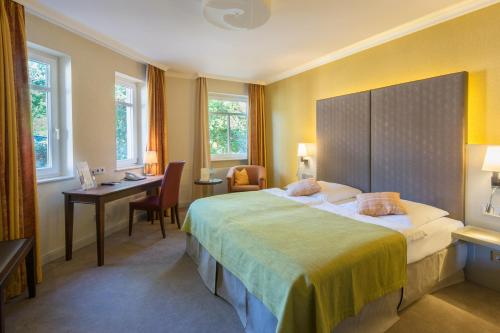 a hotel room with a large bed and a desk at Parkhotel Güldene Berge in Weißenfels