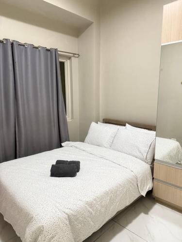 a bedroom with a white bed with a black object on it at Condo Monarch Parksuites in Manila