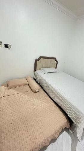 two beds in a white room with at Jati Homestay Batam Center in Batam Center