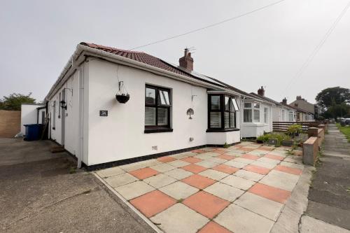 a white house with a brick sidewalk in front of it at Tawaw Bungalow South Shields in South Shields