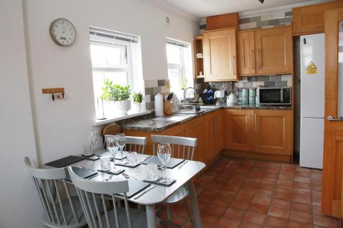a kitchen with a table with chairs and a clock on the wall at Tawaw Bungalow South Shields in South Shields