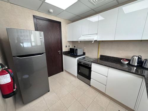 a kitchen with white cabinets and a stainless steel refrigerator at Prime Apartments Near WTC and Sheikh Zayed RD in Dubai