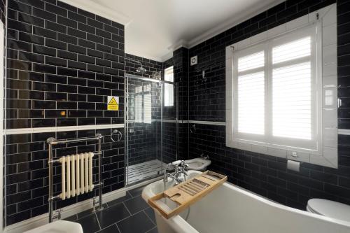 a black tiled bathroom with a tub and a sink at Tawaw Bungalow South Shields in South Shields