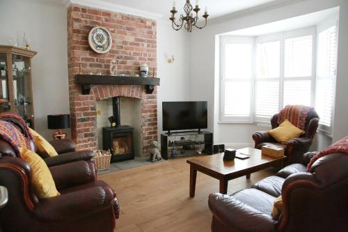 a living room with leather chairs and a fireplace at Tawaw Bungalow South Shields in South Shields