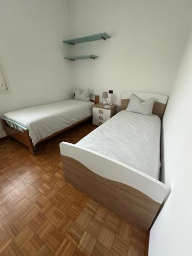 a bedroom with two beds and a wooden floor at Casa Gioia in Besano