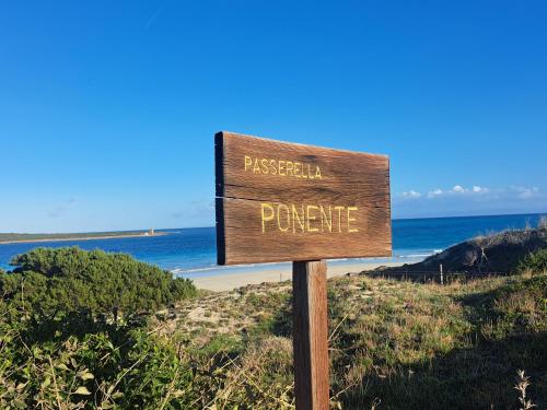 a sign at the beach with the ocean in the background at Residenza Ponente in Stintino