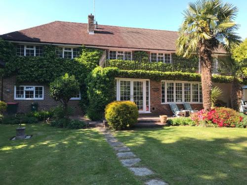 a house with a palm tree and a yard at Tanglewood Gatwick Bed & Breakfast in Crawley