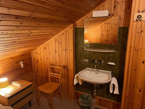 a wooden bathroom with a sink and a chair at Zimmervermietung Ackersand in Stalden