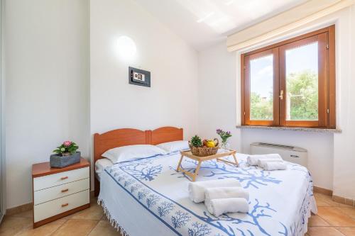 a bedroom with a bed and a table with towels on it at Villa Del Sole- in Costa Rei