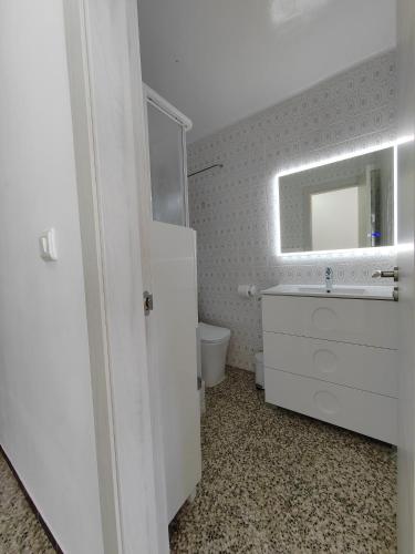 a white bathroom with a sink and a mirror at Vistal Mar in Puerto de Sagunto